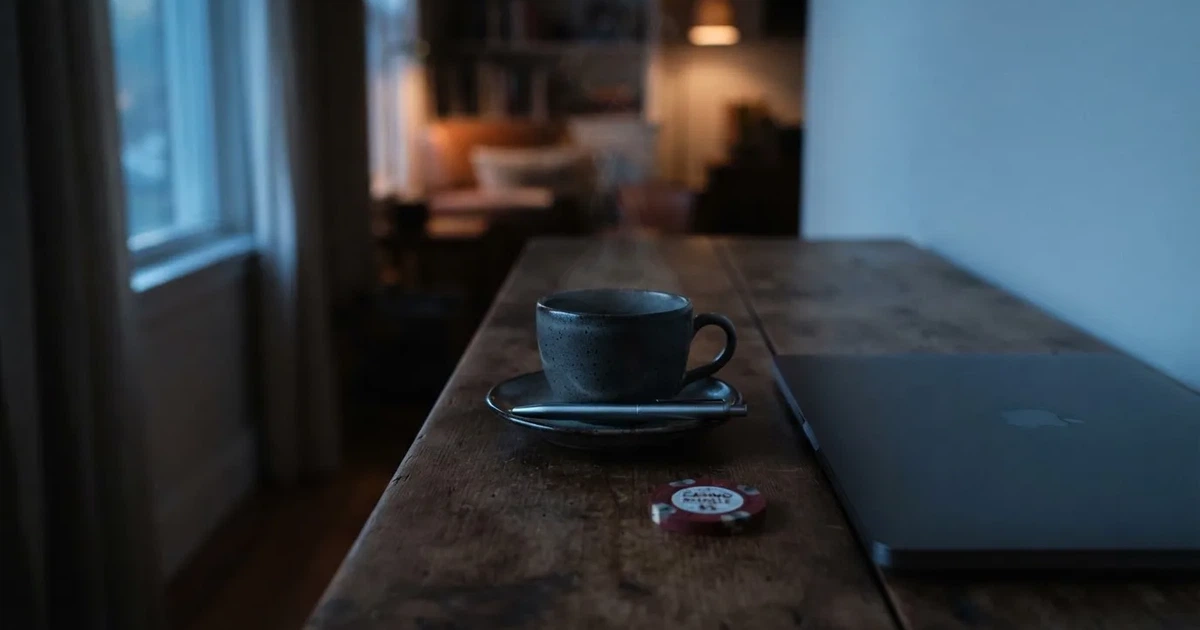 Kaffekopp och penna på ett smalt hallbord i skymning, en stängd bärbar dator vid sidan — svenska casinon med astropay