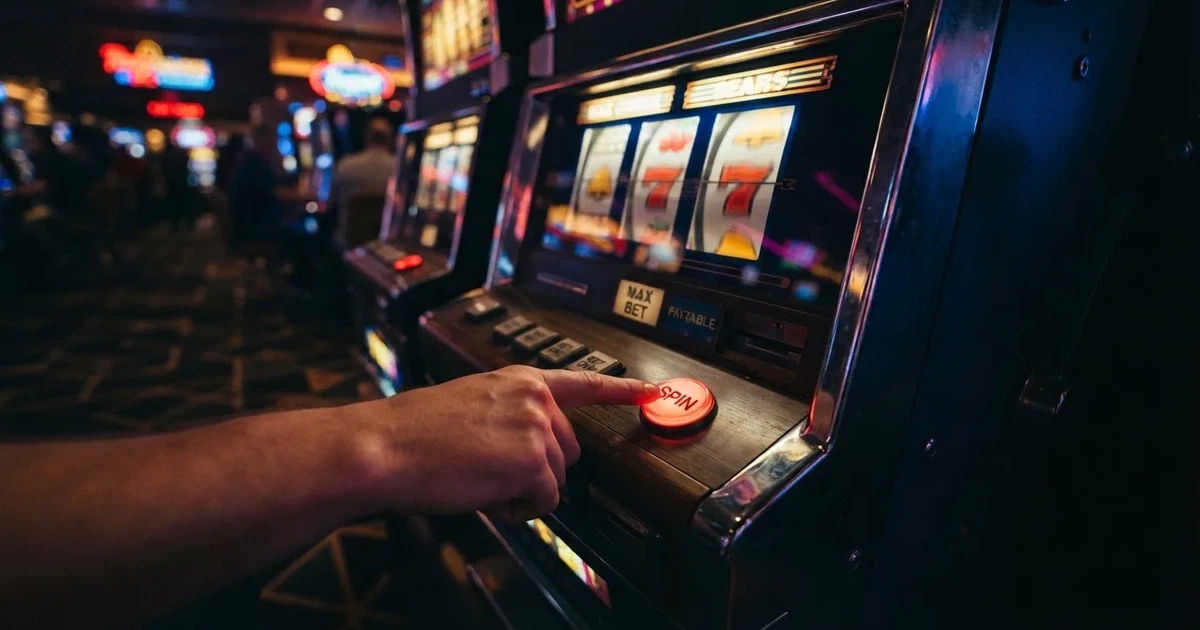 Ett finger trycker på spelautomatens klarröda knapp i dunklet, neonljus lyser runt omkring — svenska casinon med bonus